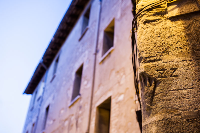 Escut amb la mà de Manlleu i la data 1582. Situat a la cantonada entre el carrer Rossell i carrer Torelló, a la sortida del barri de Dalt Vila